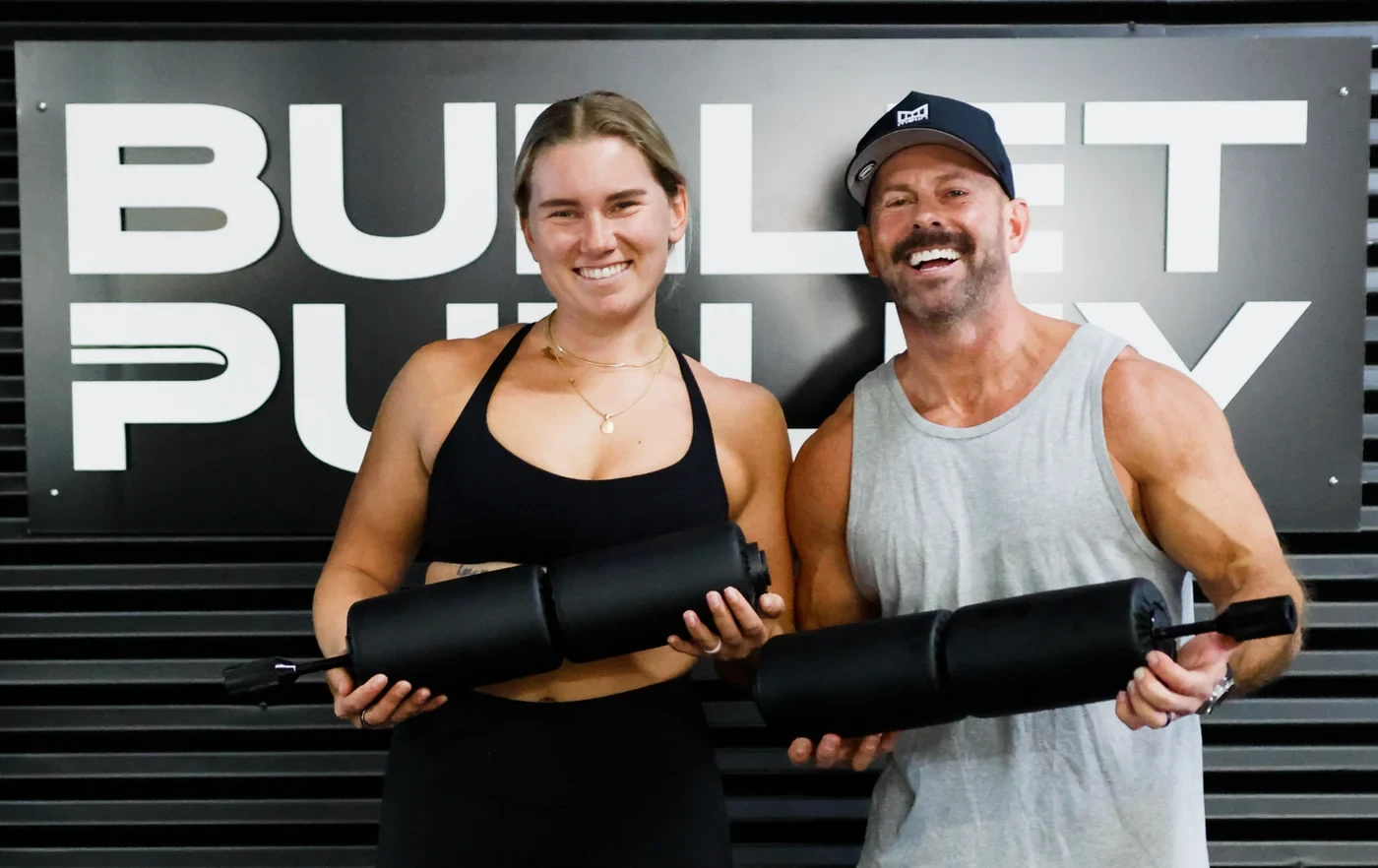Andrew and Paige, Bullet Pulley’s founders, holding the pulley in front of the Bullet Pulley sign